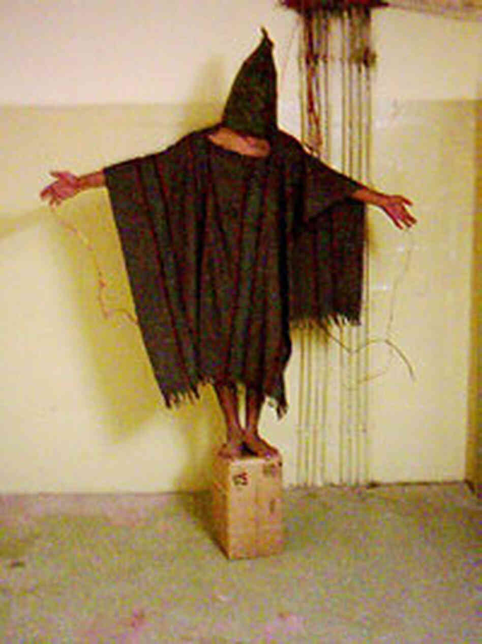 Unidentified detainee stands on a box with a bag on his head and wires attached to him at Abu Ghraib Unidentified detainee stands on a box with a bag on his head and wires attached to him at Abu Ghraib