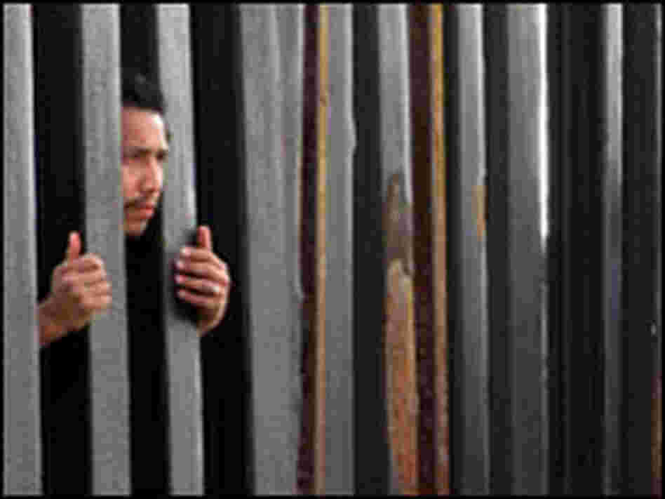 A man peers through the fence at the site where Friendship Park once was.