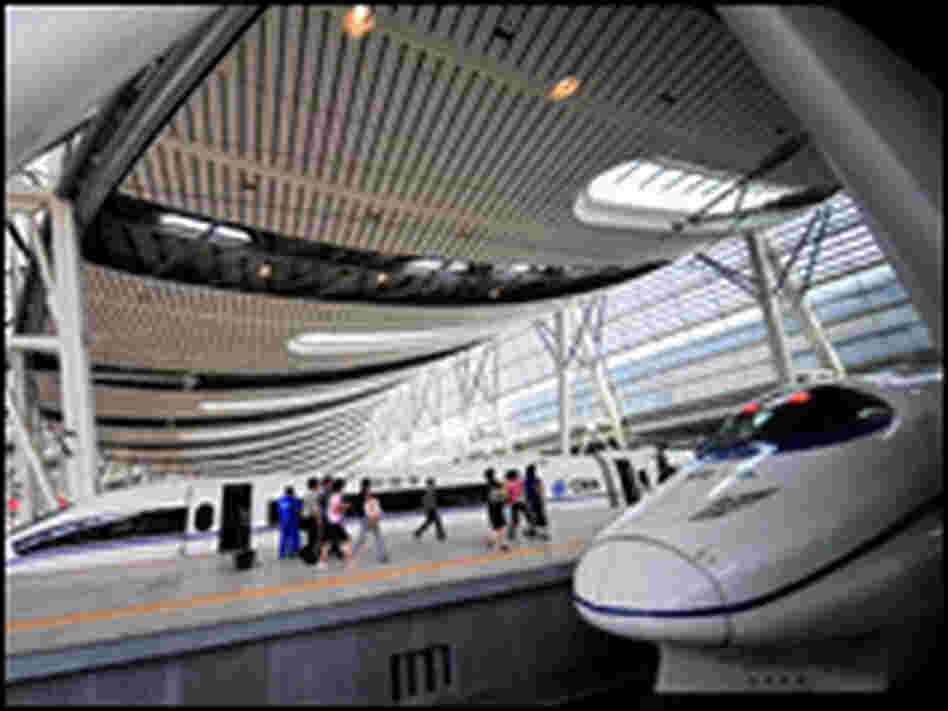 Visitors walk past bullet trains at a station in Beijing.