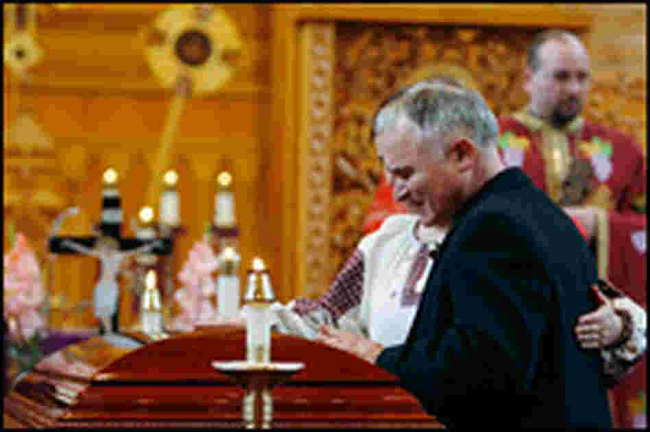Lubmyr Zobniw touches the casket of his wife, Maria Zobniw, at a funeral service in N.Y.