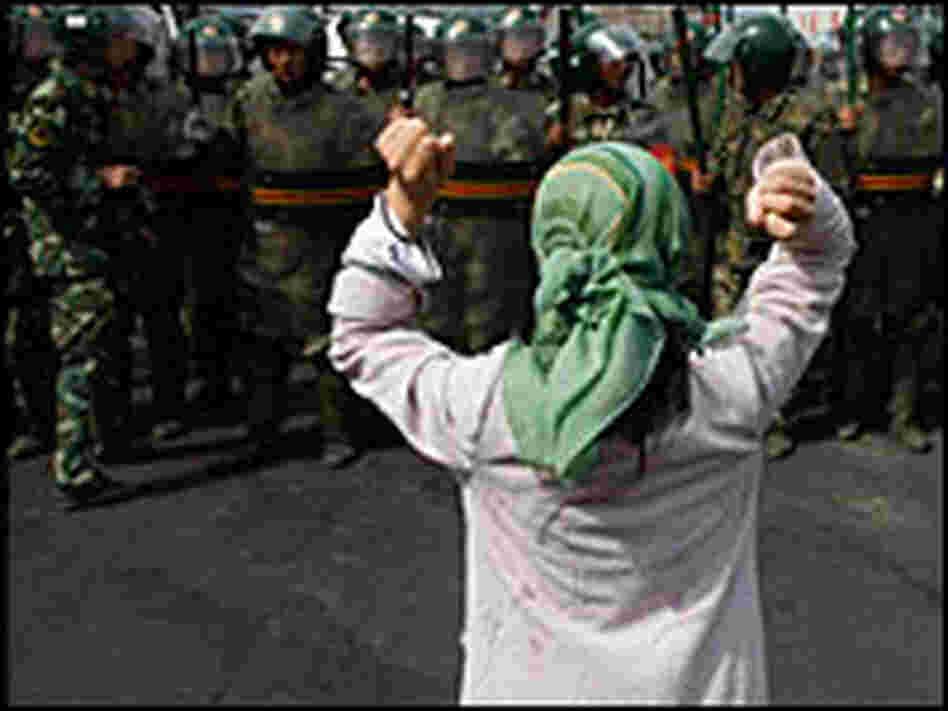 An Uighur woman protest before a group of paramilitary police An Uighur woman protest before a group of paramilitary police
