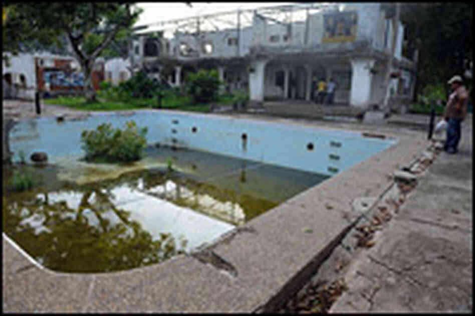 Visitors look at Escobar's swimming pool and destroyed mansion at Hacienda Napoles.