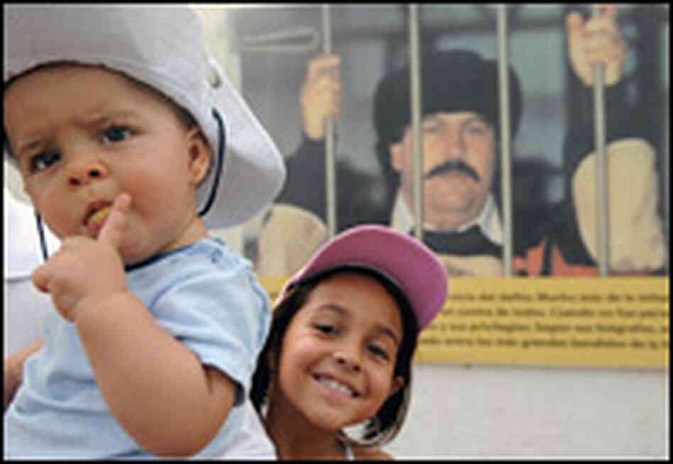 Children pose for a photograph inside the destroyed mansion of Escobar, in the background