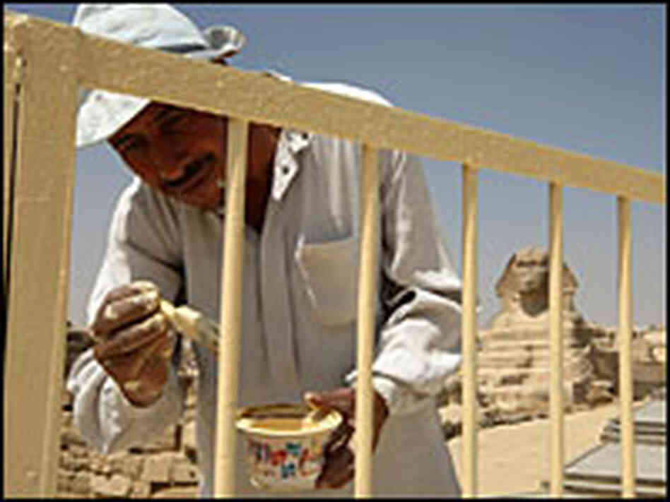 A worker applies paint to the fence surrounding the Sphinx on the outskirts of Cairo.