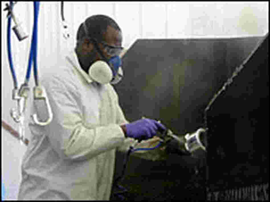 Larry Harbour of Broken Bow, Neb., sprays chrome plating on plastic wheel caps in his detail shop.