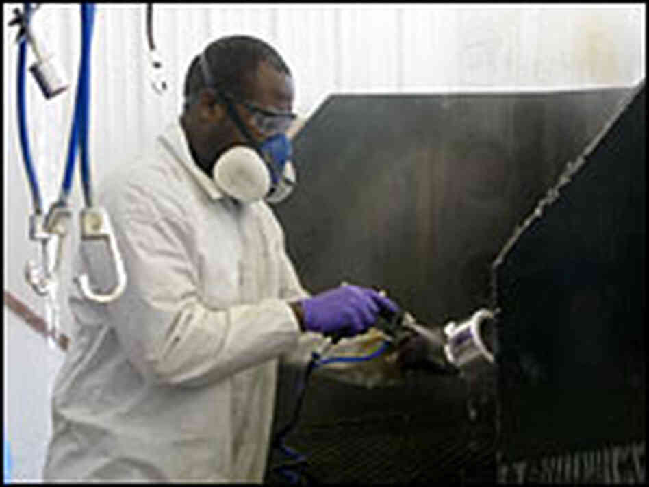 Larry Harbour of Broken Bow, Neb., sprays chrome plating on plastic wheel caps in his detail shop.