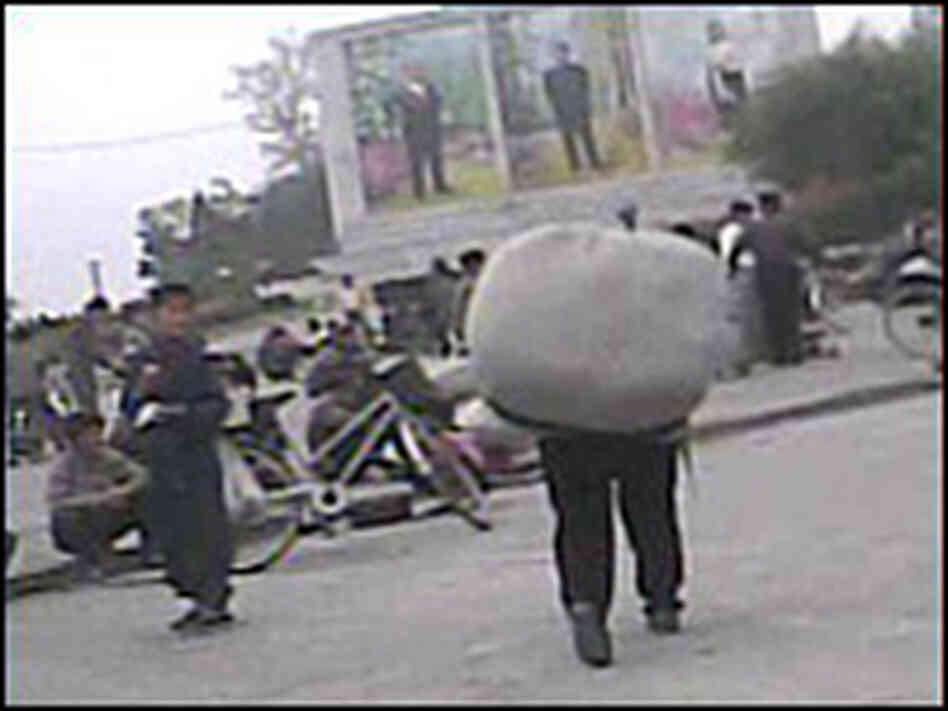 North Korean carries a heavy load of goods at the Haeju marke North Korean carries a heavy load of goods at the Haeju marke