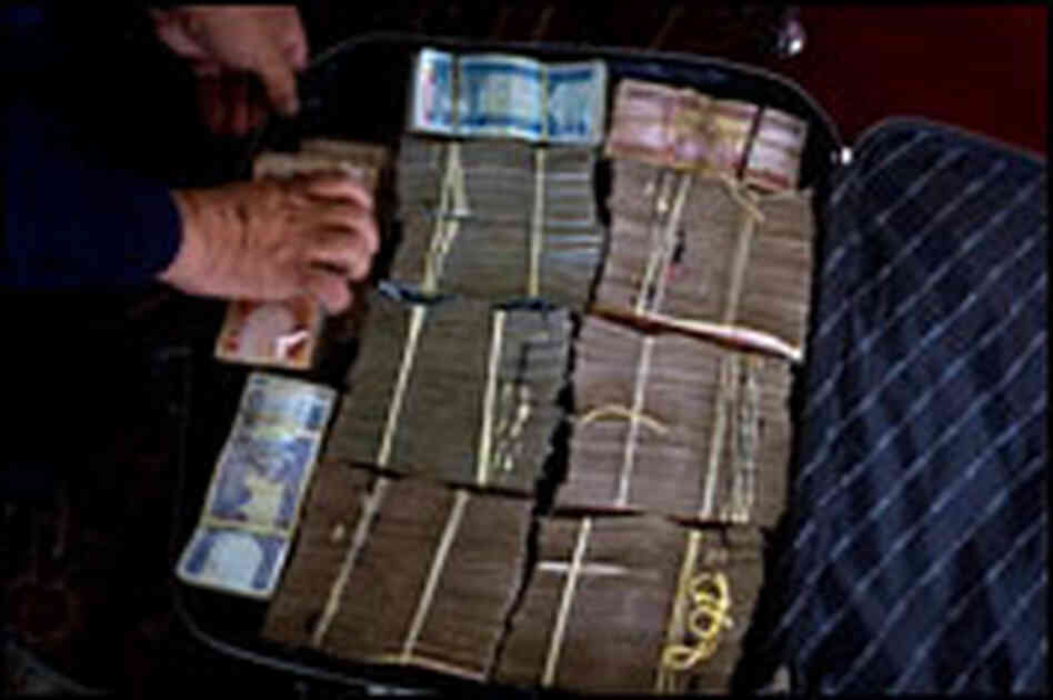 An Afghan government official arranges money in a suitcase before the reparations ceremony
