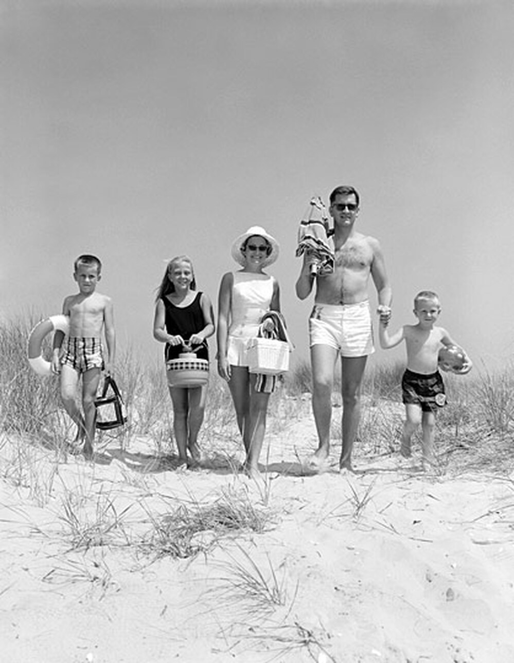 An American family of five walks toward the beach in bathing suits, circa 1960s.