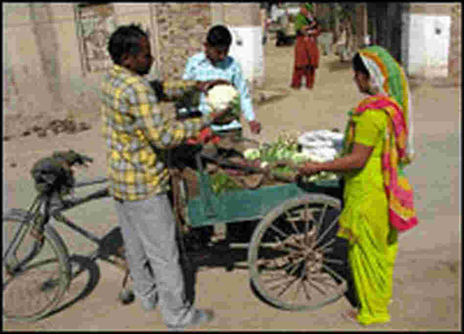 A local vendor sells his morning harvest to a villager on the street outside Sharma's compound.