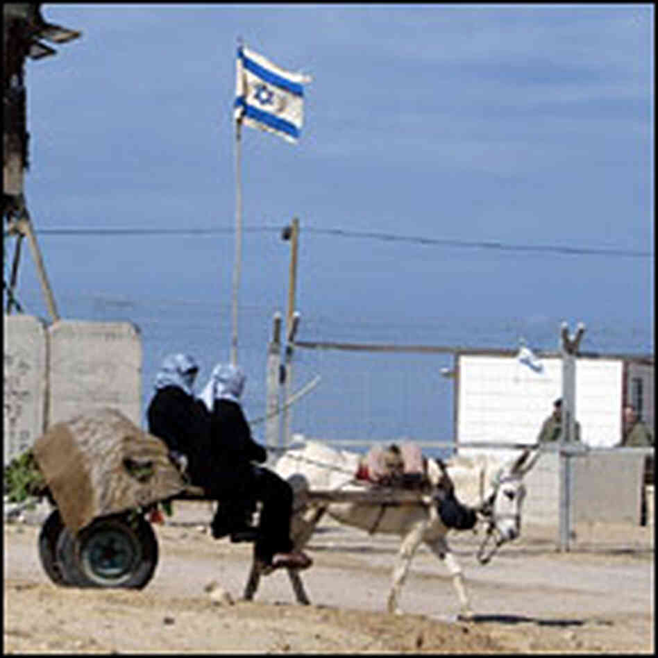 Palestinian women in a cart pass the entrance to the Jewish settlement of Shirat Hayam.