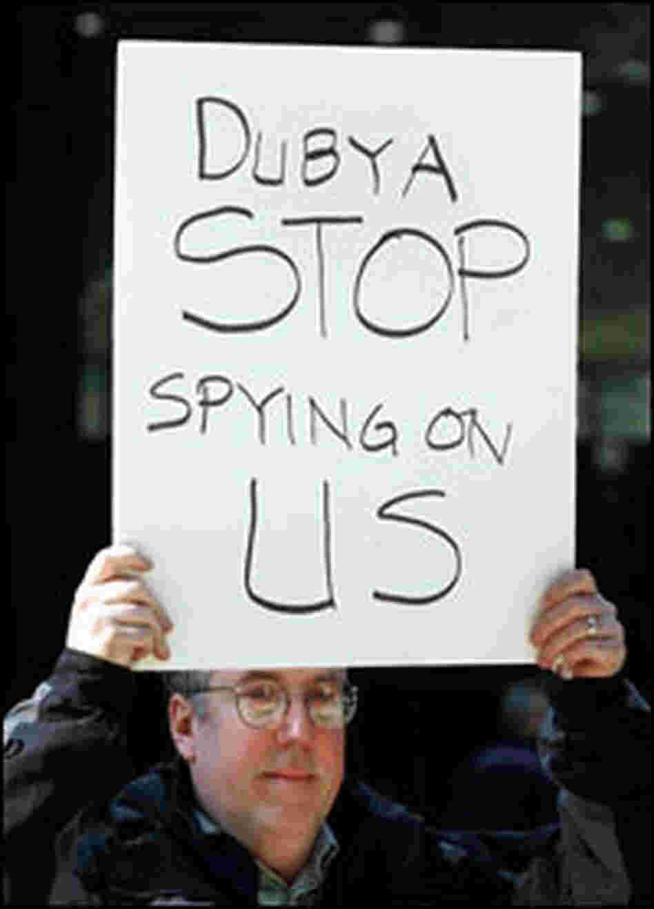 Erik Haugsnes displays a sign: 'Dubya Stop Spying on Us'