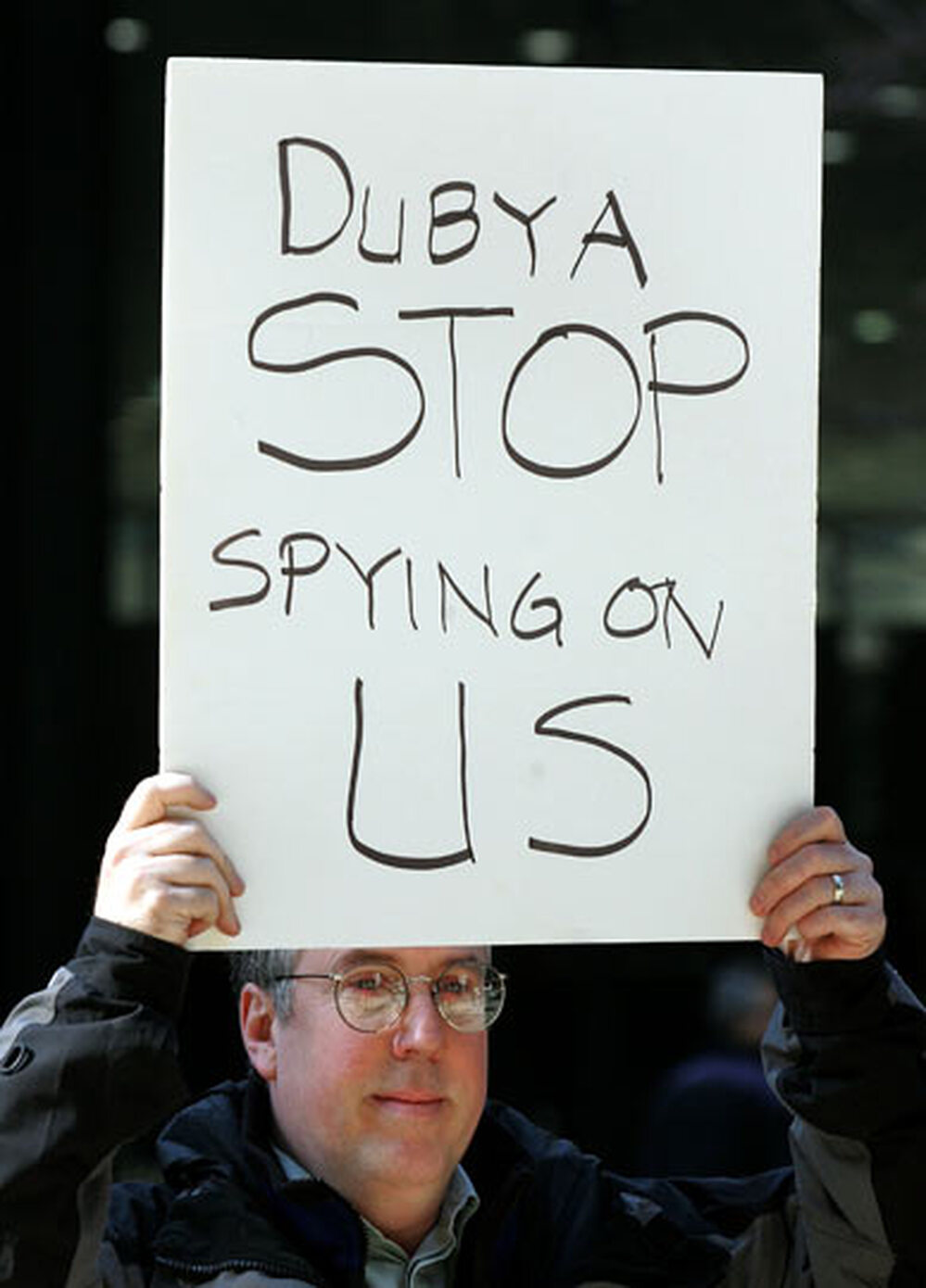 Erik Haugsnes displays a sign: 'Dubya Stop Spying on Us'