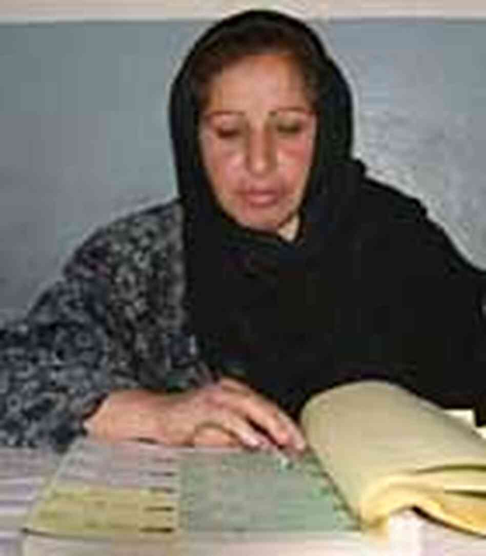 Afghan woman in Kandahar province checks register of women voters. Afghan woman in Kandahar province checks register of women voters.