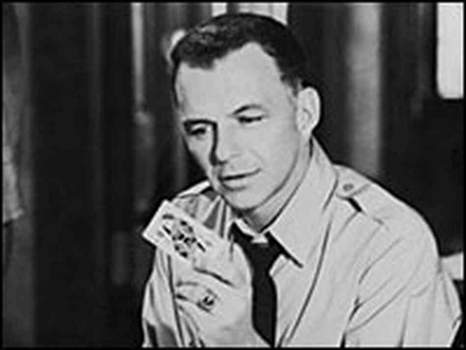Frank Sinatra holds a playing card. Frank Sinatra holds a playing card.