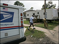 US Postal Service letter carrier Wayne Treaudo delivers mail to a trailer in front of a home in the lower ninth ward Aug. 23, 2006
