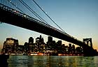 The lights of lower Manhattan blaze under the Brooklyn Bridge.