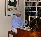 George Plimpton plays the piano in his apartment.