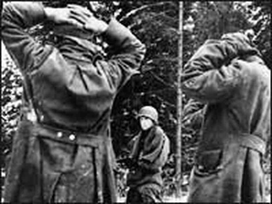 An American soldier holds German prisoners at gunpoint An American soldier holds German prisoners at gunpoint