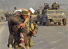 A Marine carries a wounded Iraqi.