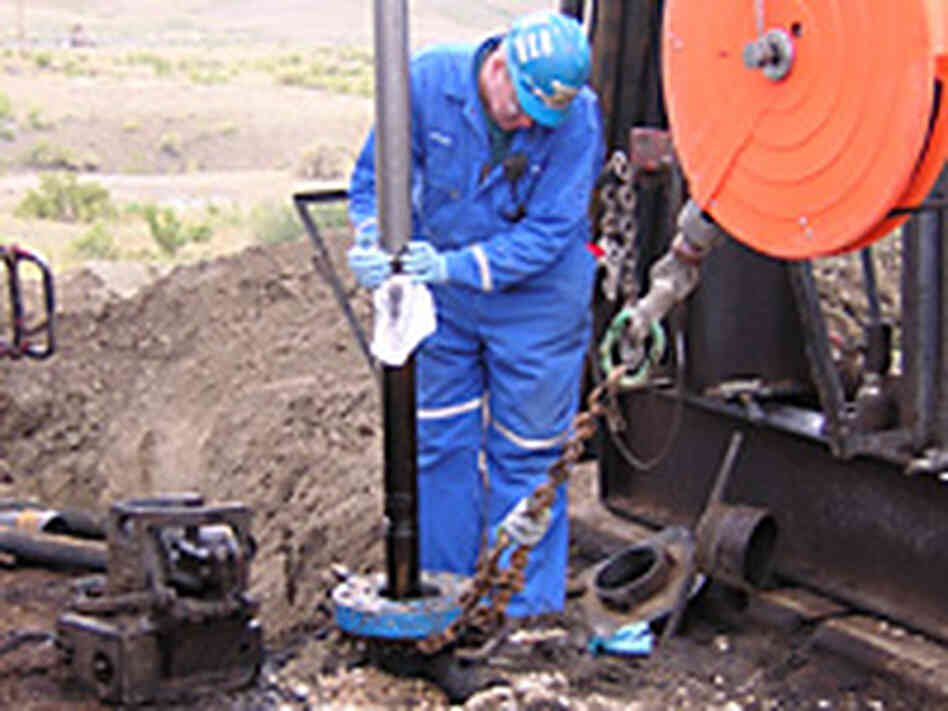 A worker wipes oil off the coring tool as it comes up from the earth. A worker wipes oil off the coring tool as it comes up from the earth.