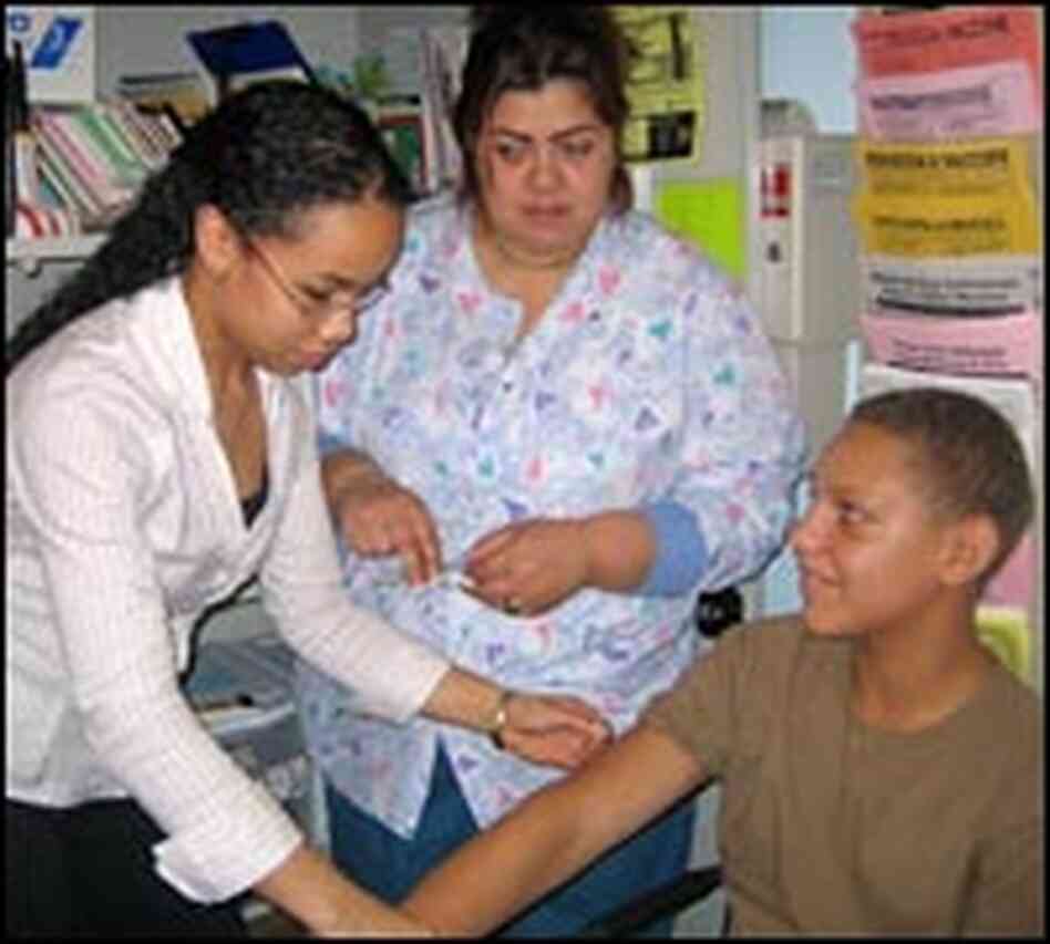Vimar Rodriguez, left, helps a nurse give a shot to a 14-year-old patient. Vimar Rodriguez, left, helps a nurse give a shot to a 14-year-old patient.
