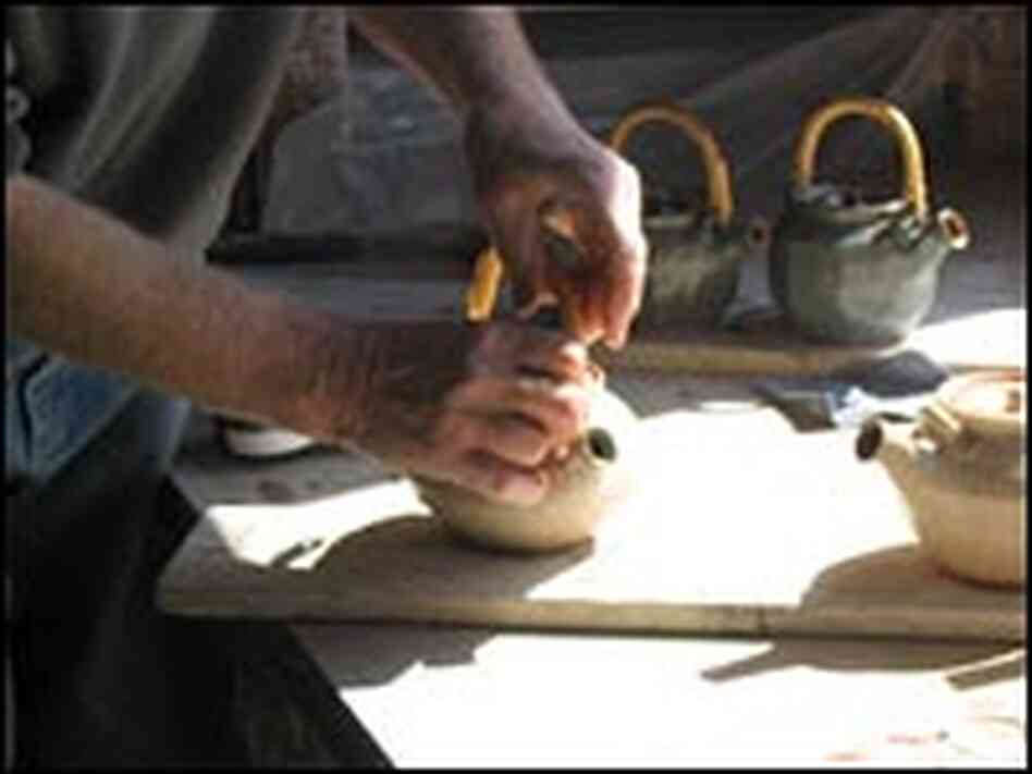 MacKenzie attaches a handle to a teapot. MacKenzie attaches a handle to a teapot.