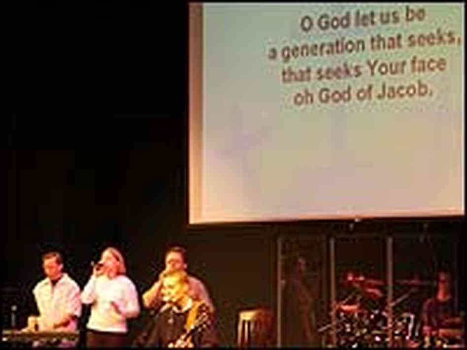 A band plays with giant biblical text in the background at Community Christian Church.