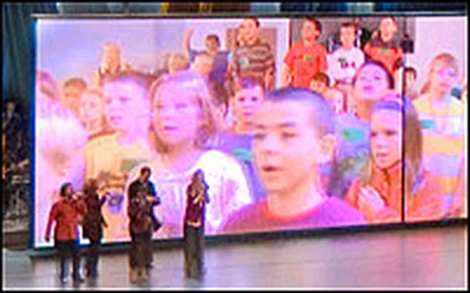 Singers are dwarfed by children on a video screen at a church service at Willow Creek.