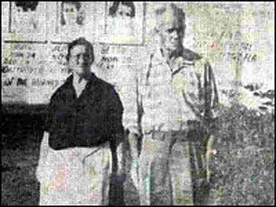 Jennie and George Sodder stand in front of the billboard.