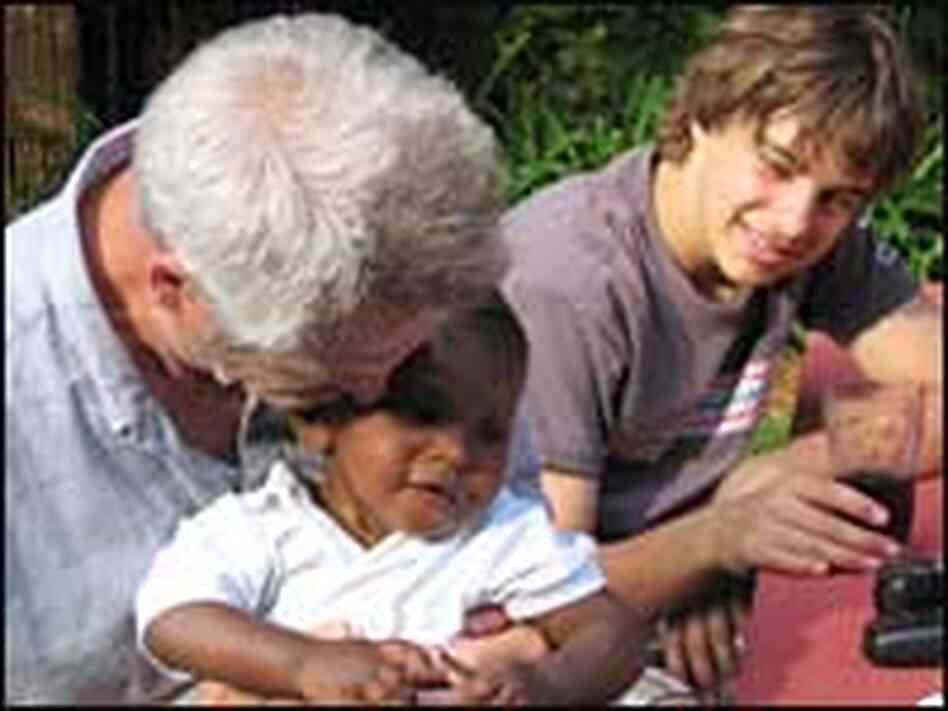 Earl Stroud holds his adopted African-American son Ethan. Big brother Jonathan Darke looks on. Earl Stroud holds his adopted African-American son Ethan. Big brother Jonathan Darke looks on.