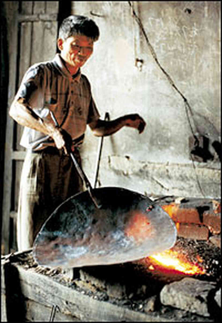 A blacksmith in Gao Tian village, in Guangxi province, makes a wok at his forge. A blacksmith in Gao Tian village, in Guangxi province, makes a wok at his forge.