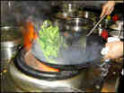 Flames roar up around a wok as it's lifted from the stove.