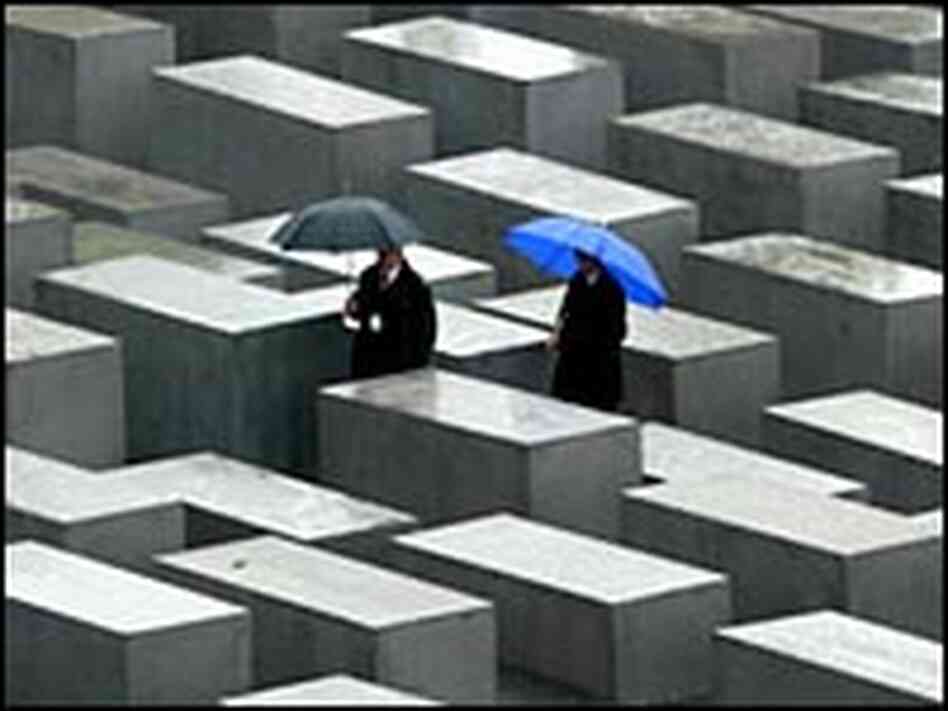 People walk between the concrete blocks of the Holocaust memorial. People walk between the concrete blocks of the Holocaust memorial.