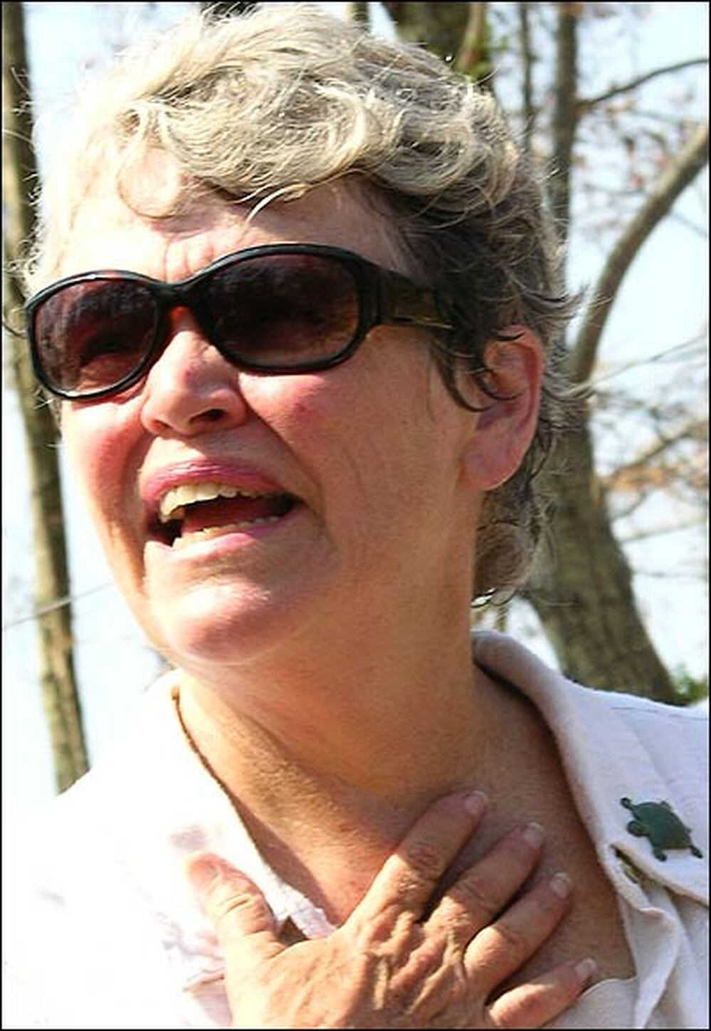 Mary Anderson Pickard, wearing sunglasses, holds a hand to her throat.