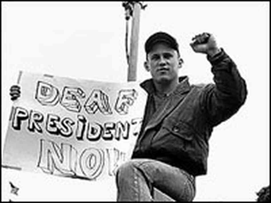 A student holds a "Deaf President Now" poster, in 1988. A student holds a "Deaf President Now" poster, in 1988.