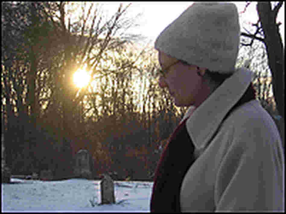 A closer shot of Anna-Lisa Cox in the Covert cemetery, the sun setting behind her.
