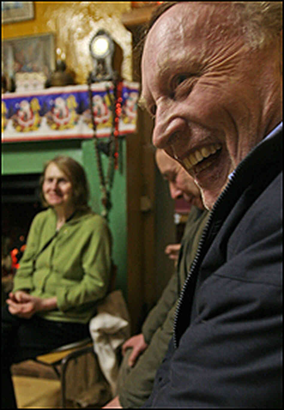 A man laughs as others cavort behind him at the rambling house. A man laughs as others cavort behind him at the rambling house.