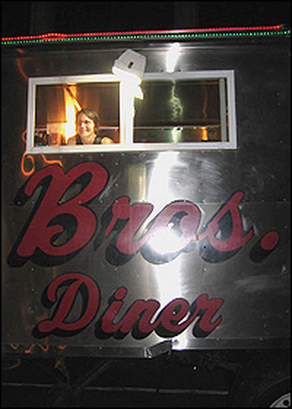 A diner peeks out from a window of the shiny, 1930s-era trailer housing the diner. A diner peeks out from a window of the shiny, 1930s-era trailer housing the diner.