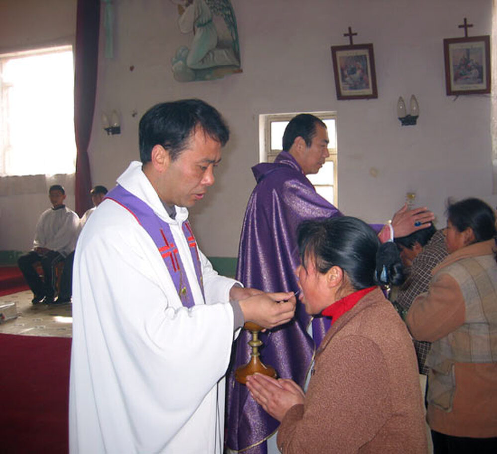 Bishop Feng and a local priest distribute the Eucharist.