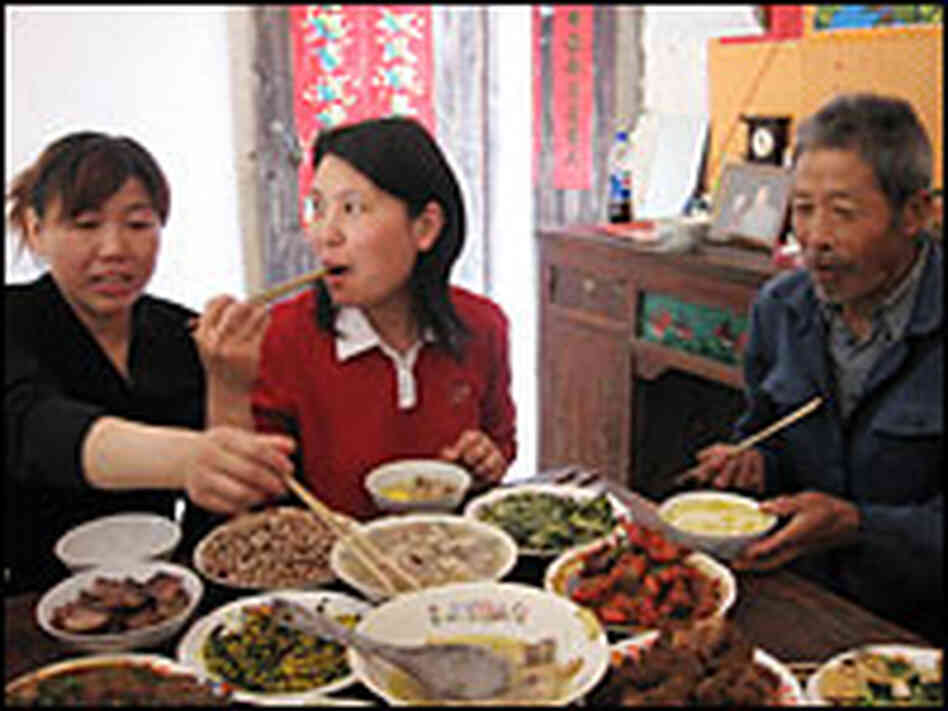 Family members enjoy a 14-dish feast in honor of the return of Wu Dexiu, left, to her home village o