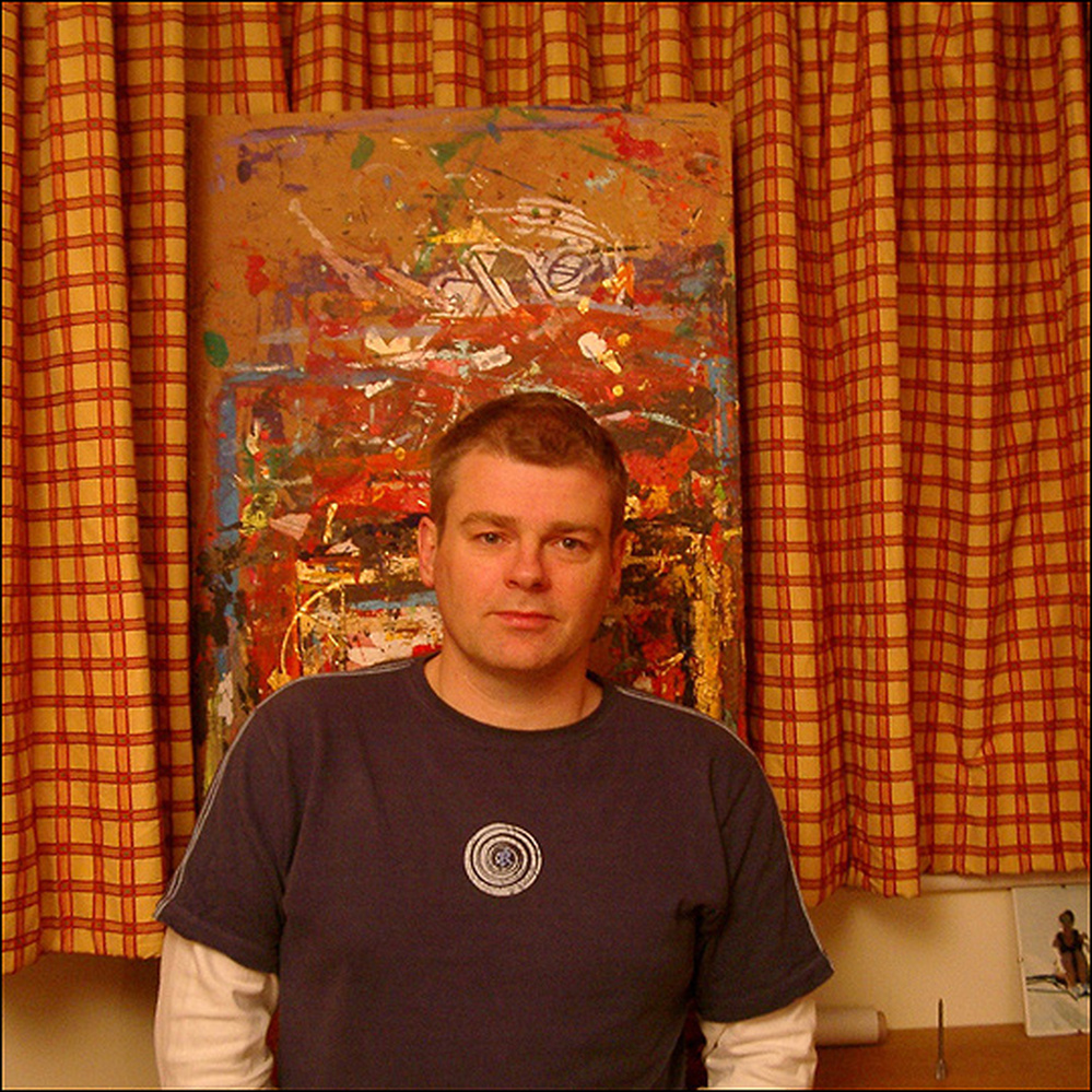 Mark Haddon stands in front of an abstract painting.