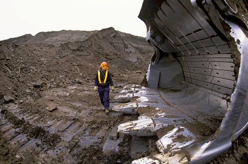 Man Standing in Oil Pit with Giant Shovel