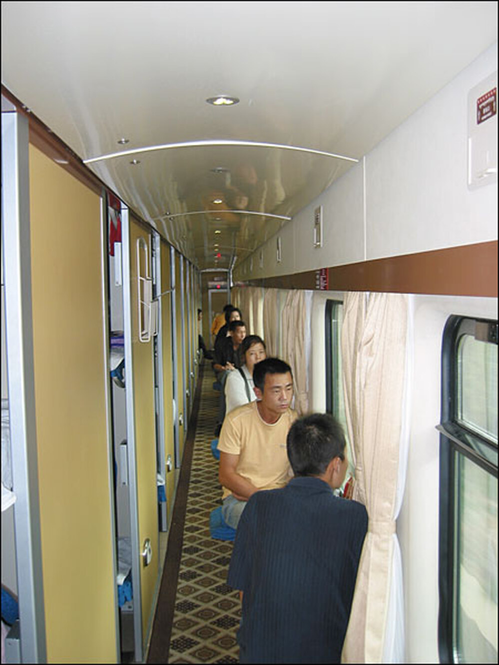 Passengers on the Beijing to Lhasa train sit outside their sleeping compartments.