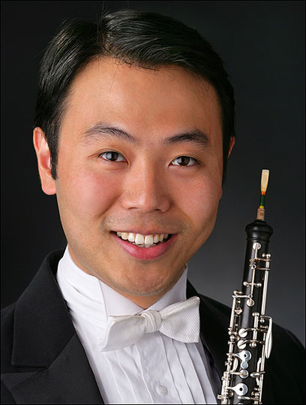 Liang Wang, pictured in tuxedo, holding his oboe.