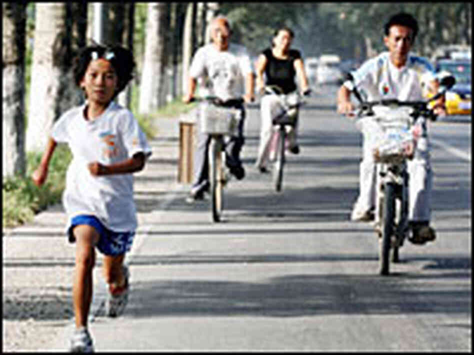 Zhang Huimin runs on a state highway in suburban Beijing, while her father, Zhang Jianmin, follows