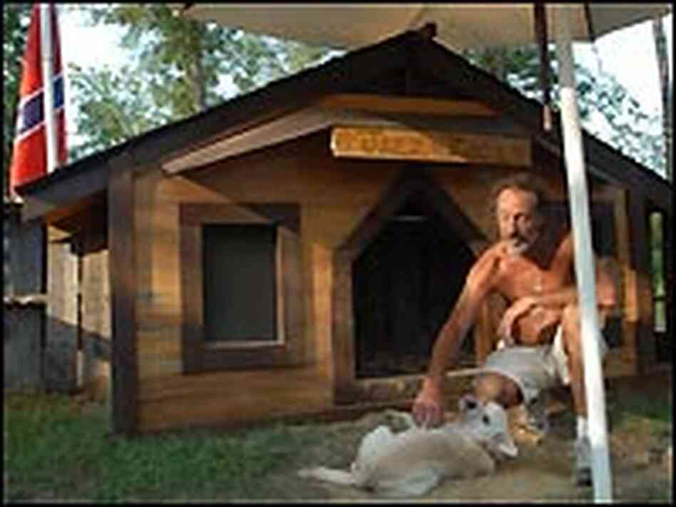 Joey Noles and his dog by the big doghouse in front of his trailer.