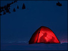 Guy reading in a tent, at dusk, on a snowy mountain. Guy reading in a tent, at dusk, on a snowy mountain.