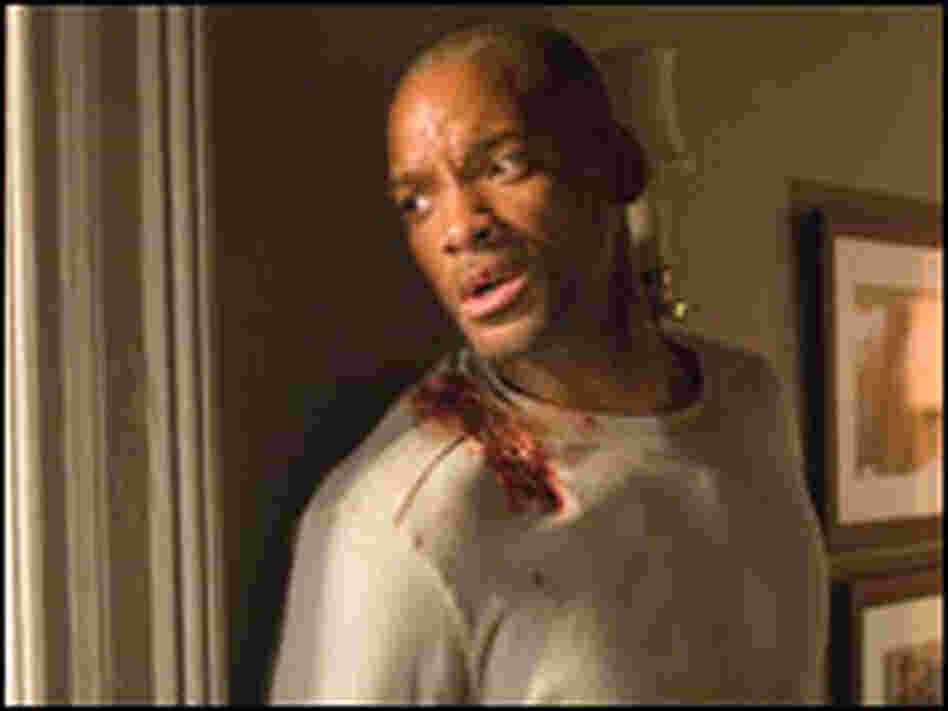 Actor Will Smith, with bloodied shoulder, looks nervously out window in "I Am Legend."