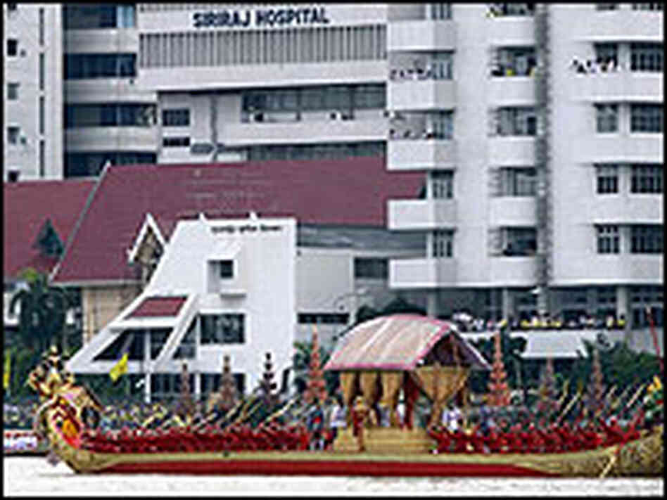Members of the Thai navy row a Royal barge on the Chao Phraya River in front of Siriraj Hospital